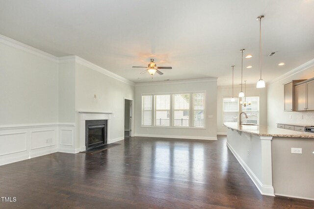 unfurnished living room featuring a glass covered fireplace, dark wood-type flooring, and ornamental molding