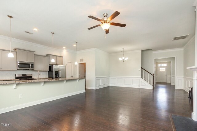 unfurnished living room with visible vents, a decorative wall, dark wood finished floors, and ceiling fan with notable chandelier