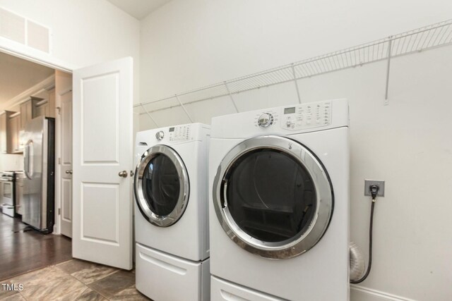 clothes washing area with visible vents, laundry area, and washer and clothes dryer