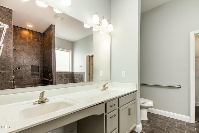 bathroom featuring double vanity, toilet, baseboards, and a sink