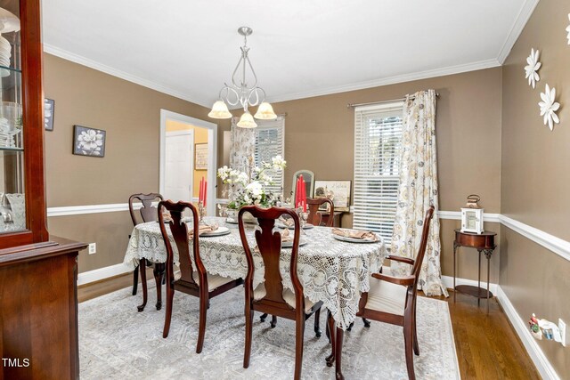 dining area with light hardwood / wood-style floors, crown molding, and an inviting chandelier