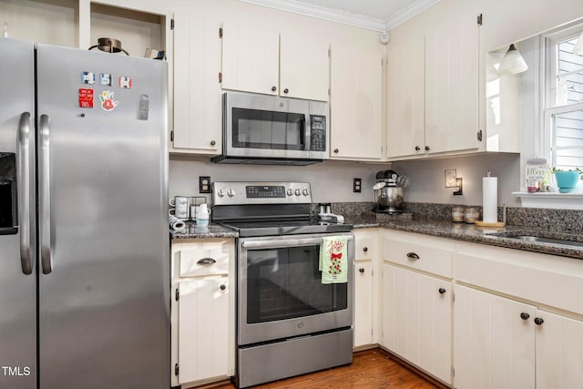 kitchen featuring white cabinetry, dark wood-type flooring, appliances with stainless steel finishes, and ornamental molding