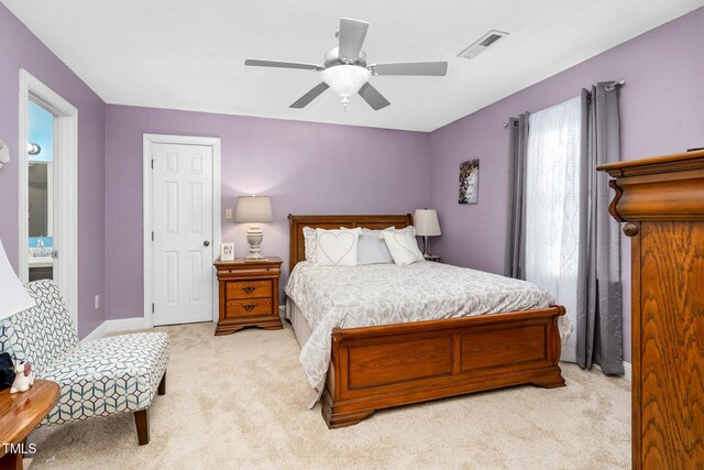 bedroom featuring light carpet, ensuite bathroom, and ceiling fan