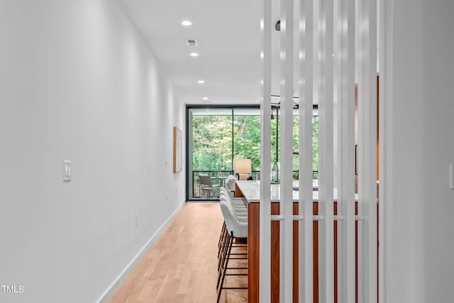 corridor featuring a wall of windows and light hardwood / wood-style flooring