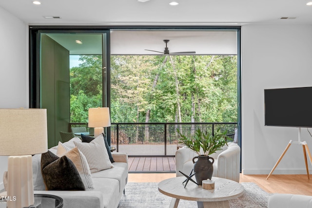 living room with light hardwood / wood-style flooring, expansive windows, a healthy amount of sunlight, and ceiling fan