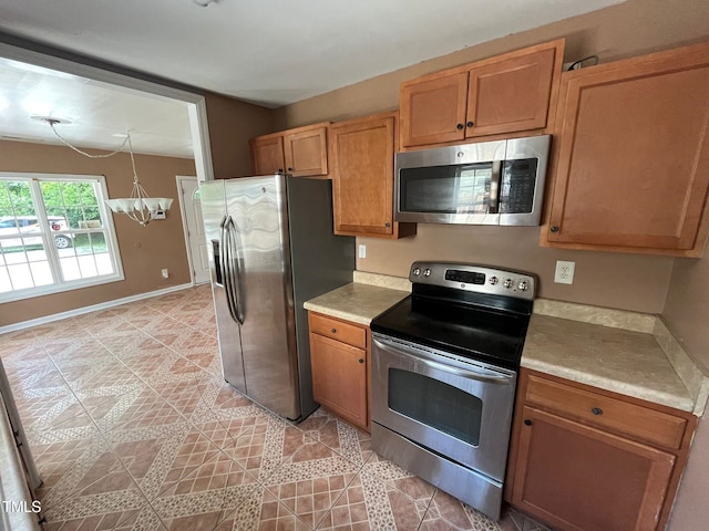 kitchen with light tile patterned floors, a chandelier, and appliances with stainless steel finishes