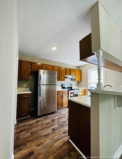 kitchen with dark hardwood / wood-style floors, kitchen peninsula, a textured ceiling, and appliances with stainless steel finishes