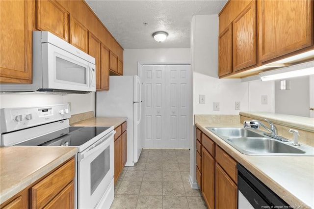 kitchen with a textured ceiling, sink, light tile patterned floors, and white appliances