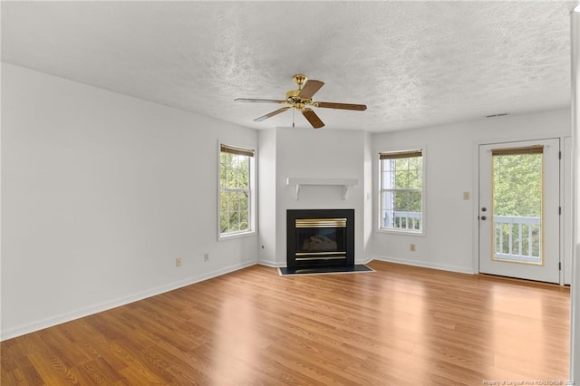 unfurnished living room featuring ceiling fan, light hardwood / wood-style floors, and a textured ceiling