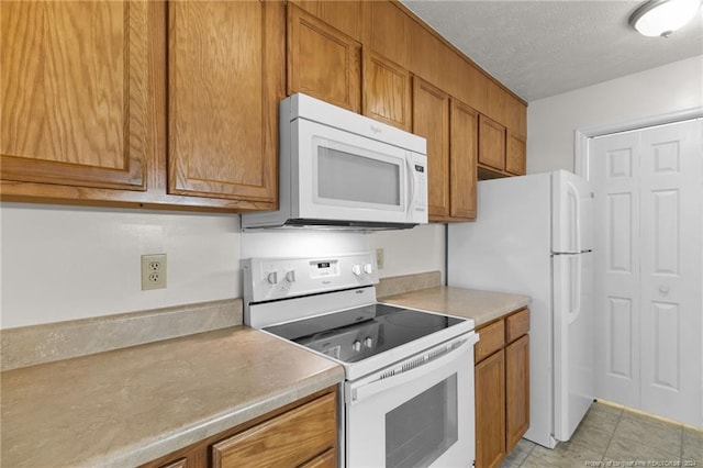 kitchen featuring light tile patterned flooring, white appliances, and a textured ceiling