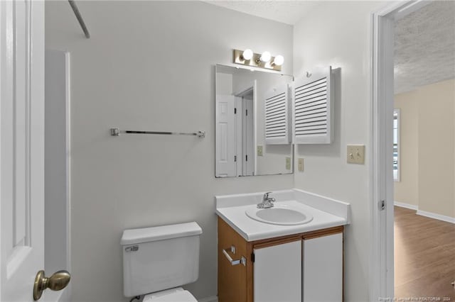 bathroom with hardwood / wood-style floors, vanity, toilet, and a textured ceiling