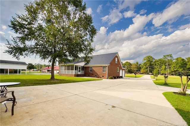 exterior space featuring a lawn, a sunroom, and a garage