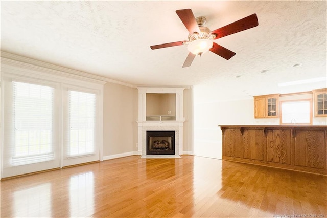 unfurnished living room featuring a textured ceiling, light hardwood / wood-style flooring, a wealth of natural light, and ceiling fan