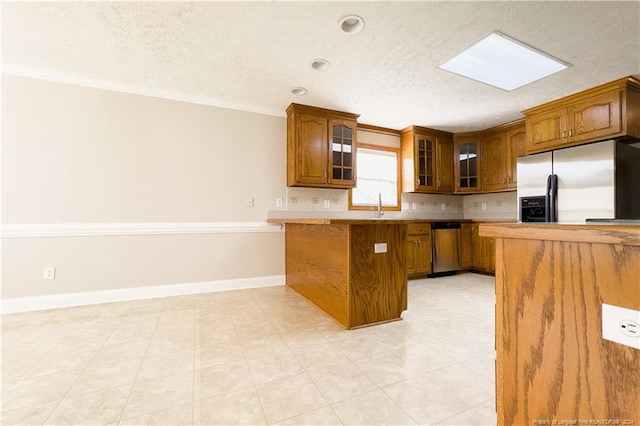 kitchen featuring sink, crown molding, a skylight, appliances with stainless steel finishes, and kitchen peninsula