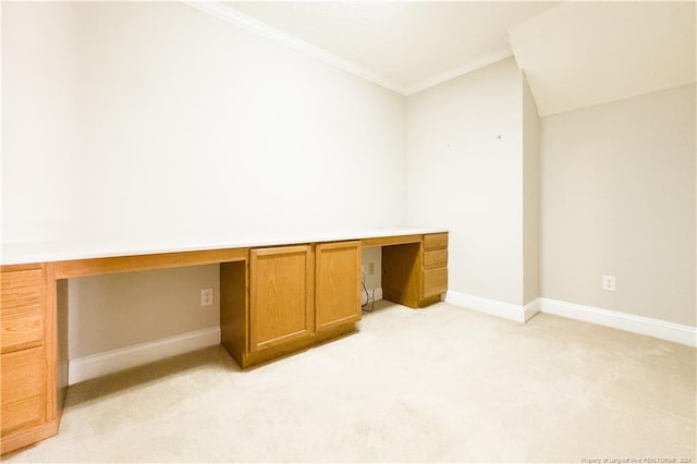 unfurnished office with crown molding, light colored carpet, built in desk, and vaulted ceiling