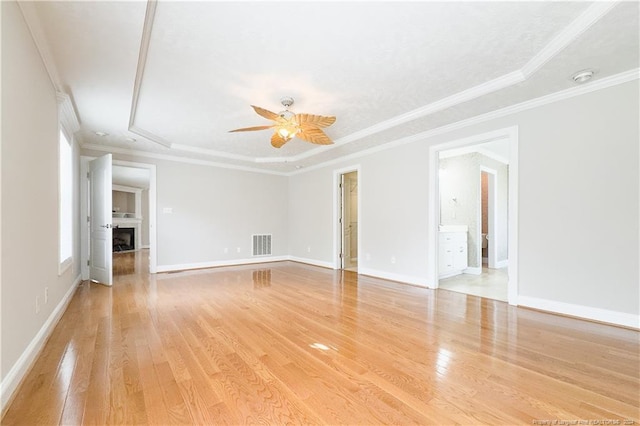 unfurnished room featuring ceiling fan, a raised ceiling, light wood-type flooring, and crown molding