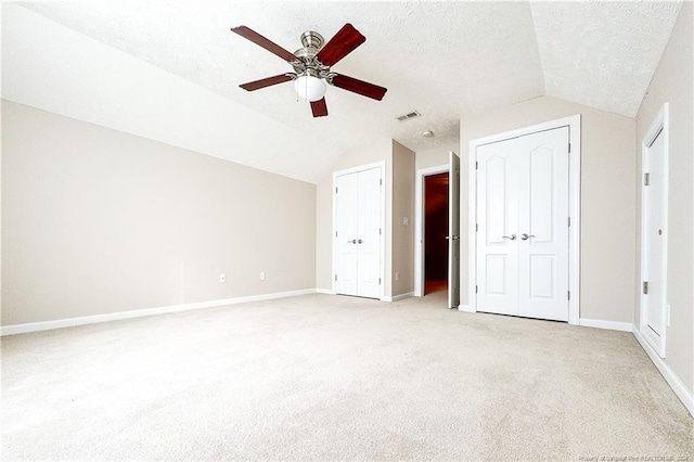 unfurnished bedroom with ceiling fan, lofted ceiling, a textured ceiling, and light carpet