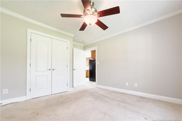 unfurnished bedroom featuring ceiling fan, black fridge, light colored carpet, a closet, and ornamental molding