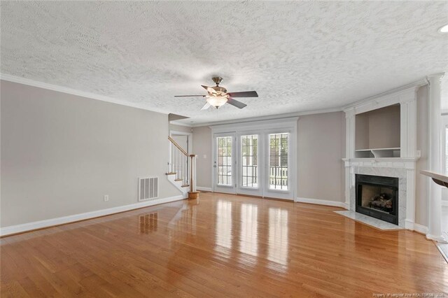 4419 Cameron Rd, Hope Mills, NC 28348 - unfurnished living room featuring light wood-style floors, stairs, a ceiling fan, a fireplace, and a textured ceiling