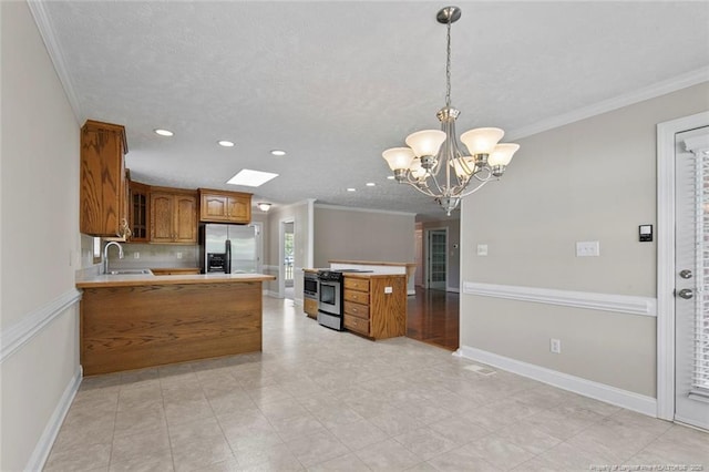 4419 Cameron Rd, Hope Mills, NC 28348 - kitchen featuring stainless steel appliances, brown cabinetry, a peninsula, ornamental molding, and a chandelier