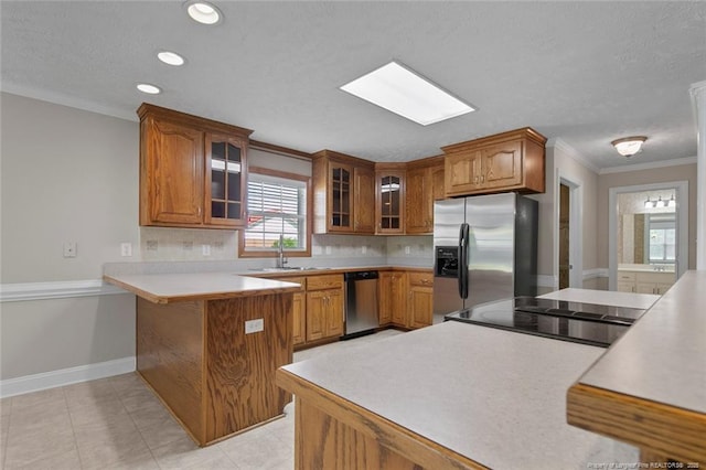4419 Cameron Rd, Hope Mills, NC 28348 - kitchen featuring stainless steel appliances, a peninsula, crown molding, brown cabinetry, and glass insert cabinets