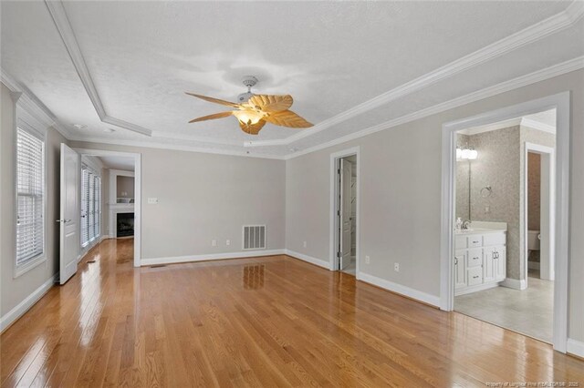 4419 Cameron Rd, Hope Mills, NC 28348 - empty room featuring light wood-style flooring, ceiling fan, a tray ceiling, crown molding, and a fireplace