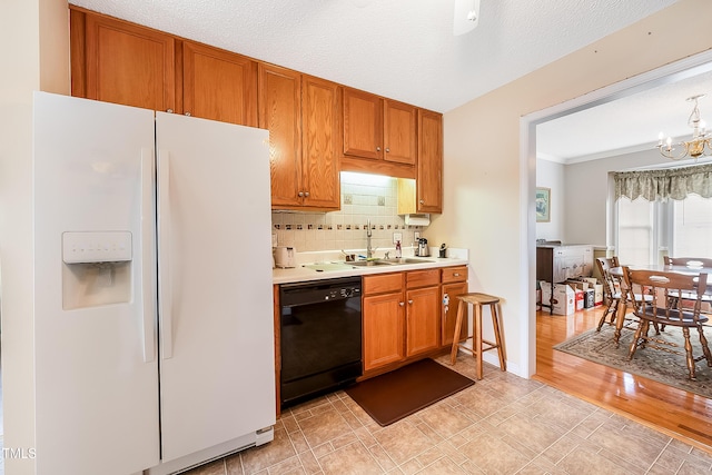 kitchen featuring backsplash, sink, a notable chandelier, black dishwasher, and white fridge with ice dispenser