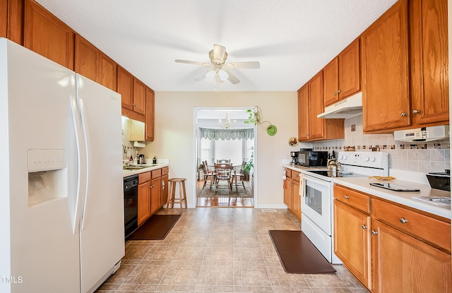 kitchen featuring sink, backsplash, a textured ceiling, white appliances, and ceiling fan with notable chandelier