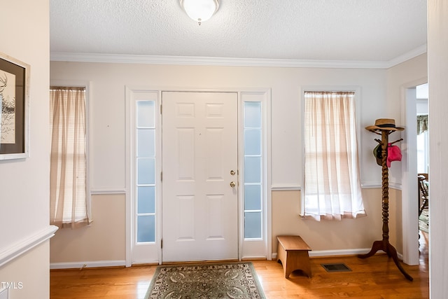 foyer entrance featuring crown molding, light hardwood / wood-style floors, and a textured ceiling