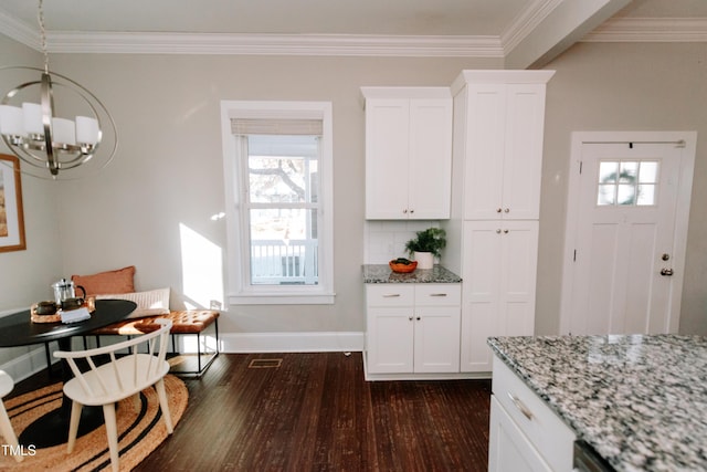 dining room with crown molding, dark hardwood / wood-style flooring, a healthy amount of sunlight, and a notable chandelier