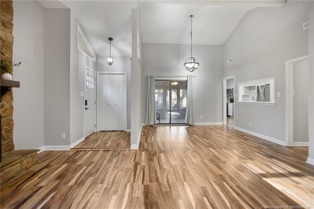 entrance foyer featuring hardwood / wood-style floors, high vaulted ceiling, and an inviting chandelier
