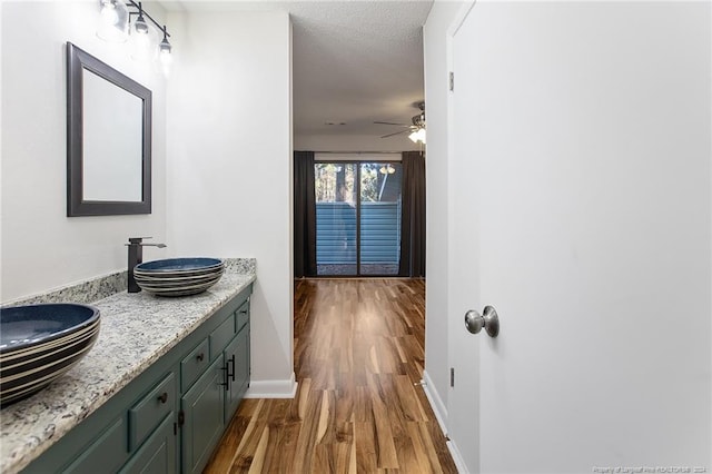 bathroom featuring vanity, a textured ceiling, hardwood / wood-style flooring, and ceiling fan
