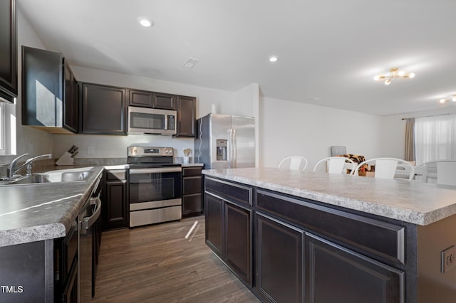 kitchen featuring a center island, dark wood-type flooring, sink, a breakfast bar area, and stainless steel appliances