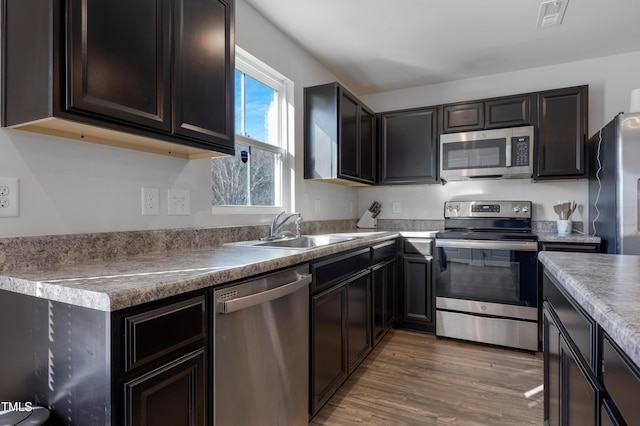 kitchen with dark brown cabinets, sink, dark hardwood / wood-style floors, and appliances with stainless steel finishes