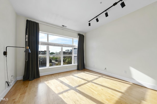 empty room with rail lighting and light wood-type flooring