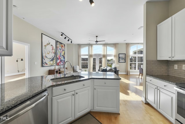 kitchen featuring sink, dark stone countertops, appliances with stainless steel finishes, decorative backsplash, and white cabinets