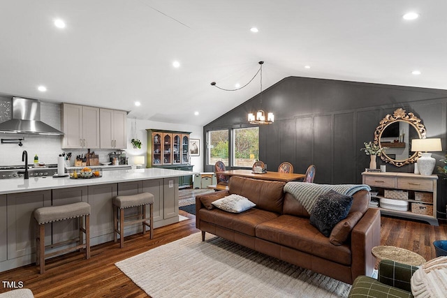 living room with dark wood-type flooring, lofted ceiling, and an inviting chandelier