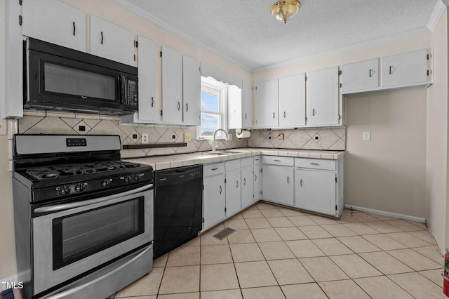 kitchen with tasteful backsplash, tile countertops, white cabinets, and black appliances