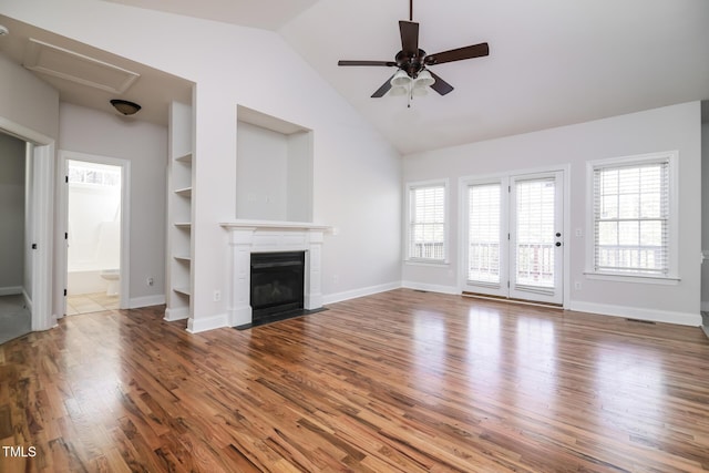 unfurnished living room with hardwood / wood-style flooring, ceiling fan, built in features, and vaulted ceiling