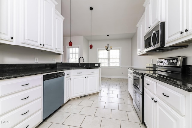 kitchen featuring white cabinets, hanging light fixtures, appliances with stainless steel finishes, and dark stone counters