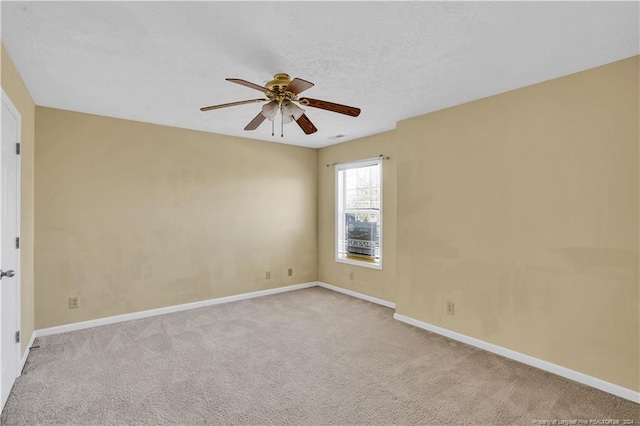 empty room with ceiling fan, light colored carpet, and a textured ceiling