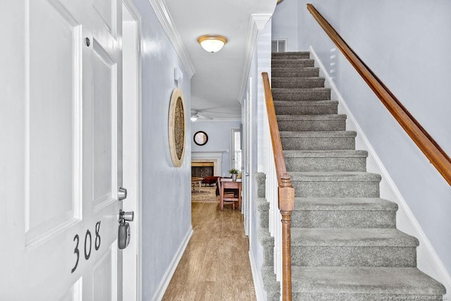 stairway with hardwood / wood-style floors, ceiling fan, and crown molding