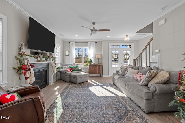 living room with a fireplace, ceiling fan, light hardwood / wood-style flooring, and ornamental molding