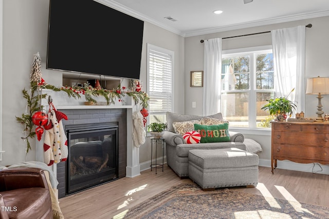 sitting room with a brick fireplace, plenty of natural light, and light hardwood / wood-style flooring