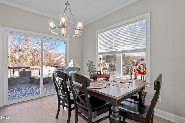 dining area with an inviting chandelier, ornamental molding, and light wood-type flooring