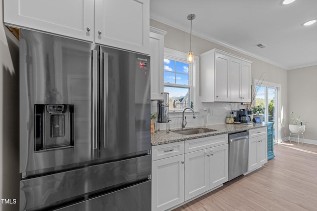 kitchen featuring pendant lighting, backsplash, sink, white cabinetry, and stainless steel appliances