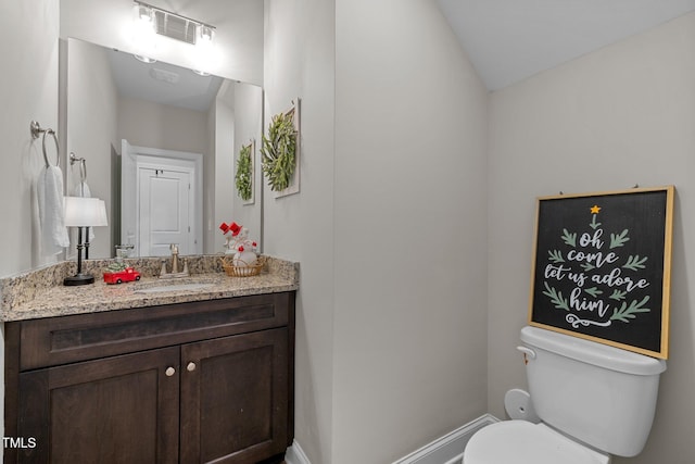 bathroom featuring vanity, toilet, and vaulted ceiling