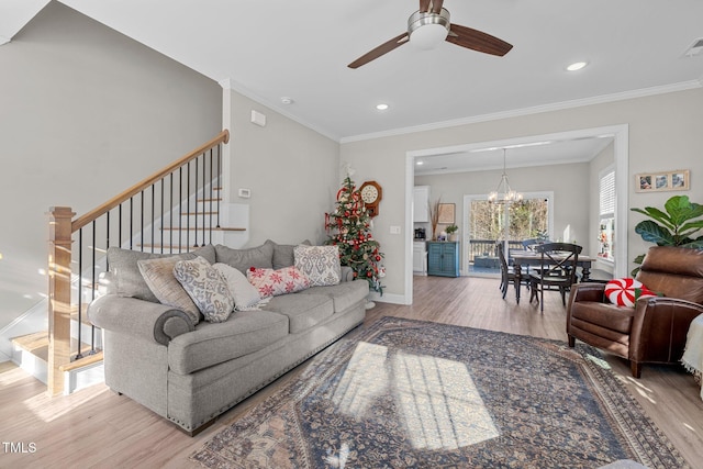 living room featuring ceiling fan with notable chandelier, light hardwood / wood-style floors, and crown molding