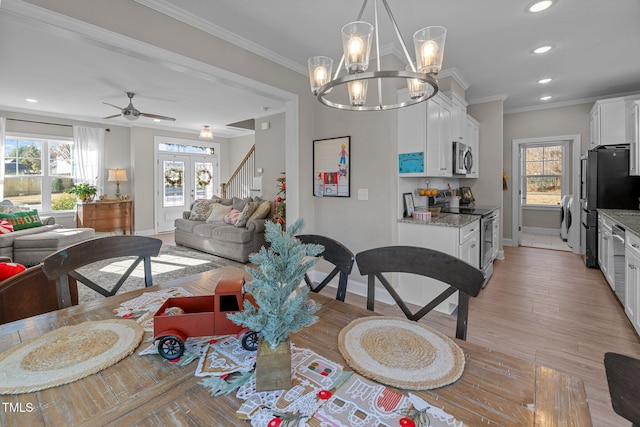 dining space featuring french doors, light hardwood / wood-style flooring, washer / dryer, ceiling fan with notable chandelier, and ornamental molding