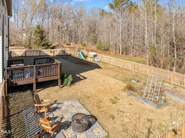 view of yard featuring a playground, an outdoor fire pit, and a wooden deck